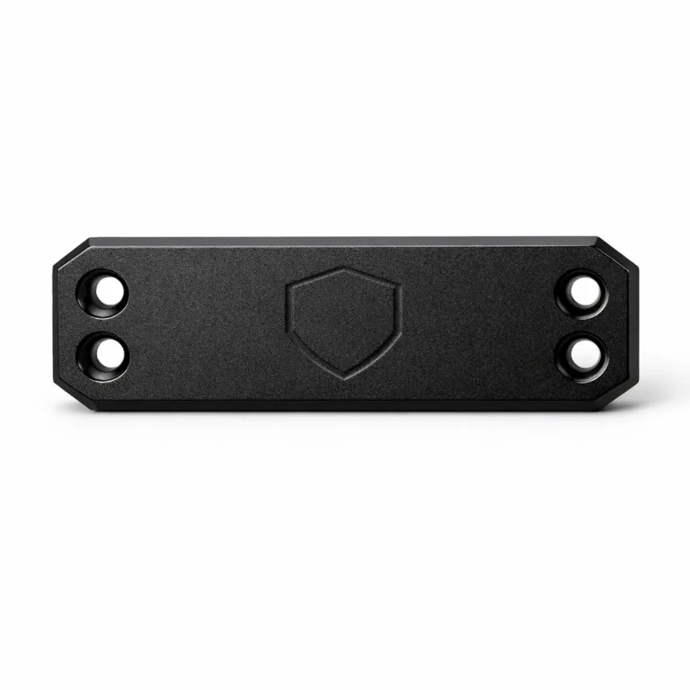 This bracelet tag is crafted from anodized aluminum with a sandblasted matte black finish. The beveled edges and double sewing holes offer a refined look, while a subtle debossed emblem shape accents the front.