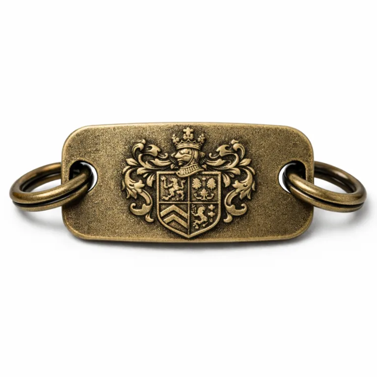 Antique brass crest bracelet tag with a sandblasted matte surface for a vintage look, featuring a deep embossed crest emblem, thicker profile, and split ring. Detailed studio shot captures every texture for true-to-life product presentation.