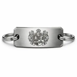 A high-resolution image of a brushed stainless steel crest bracelet tag, featuring a laser engraved crest emblem and beveled edge. The tag is attached to a split ring. Studio lighting enhances the sharp details and realistic finish.