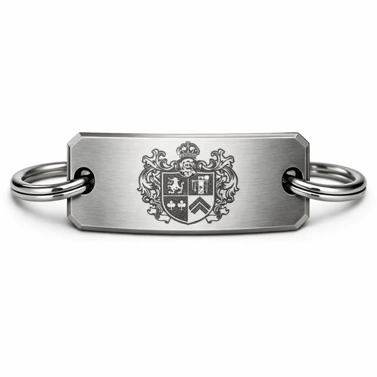 A high-resolution image of a brushed stainless steel crest bracelet tag, featuring a laser engraved crest emblem and beveled edge. The tag is attached to a split ring. Studio lighting enhances the sharp details and realistic finish.