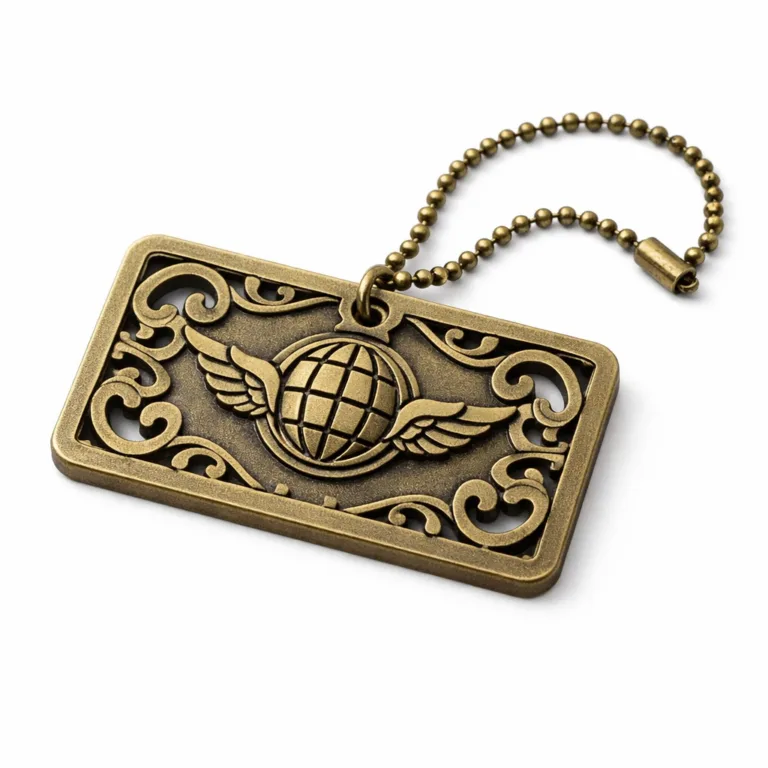 A realistic studio shot of a cut-out pattern zinc alloy luggage tag plated in antique brass with a sandblasted matte finish, thick profile, and a blank embossed emblem. Includes a ball chain for attachment. Shown on a white background.