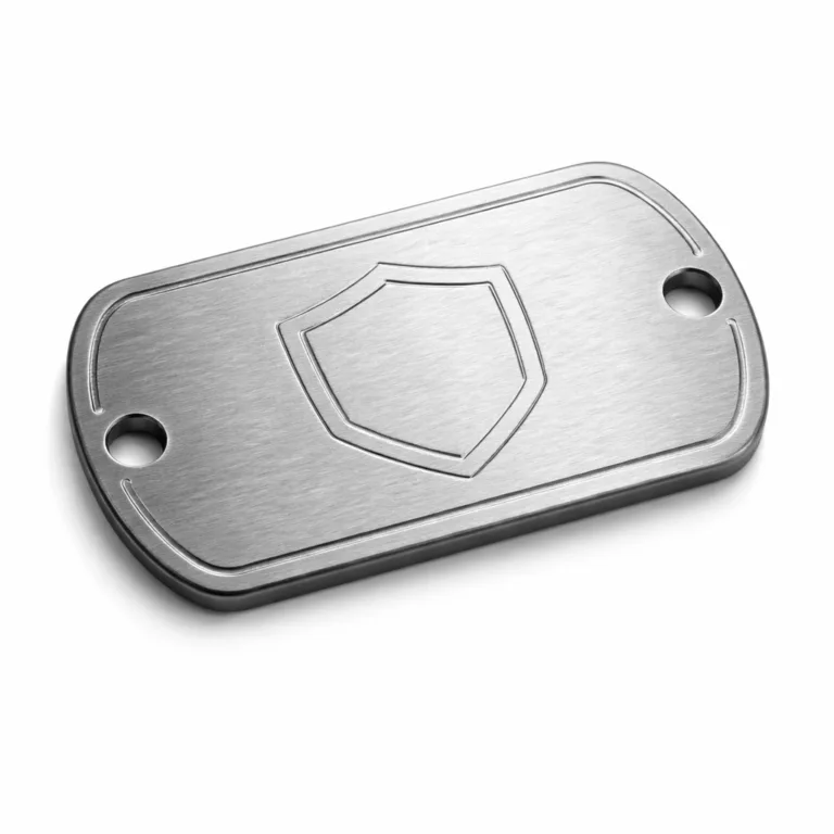 A high-detail product photo of a brushed stainless steel dog tag with matte finish, featuring rounded corners, double holes for chain attachment, and a subtle blank emblem engraving, suitable for tactical use.