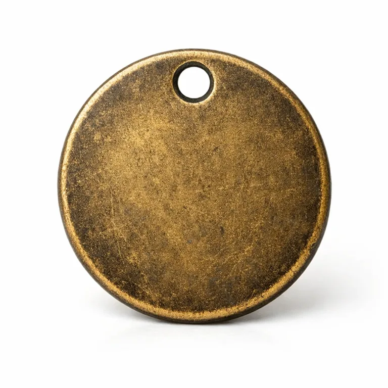 Antique brass dog tag featuring a muted, aged finish and soft round edges. The tag showcases a delicate etched surface for a touch of texture. Designed with a single hole for ball chain or ring attachment.