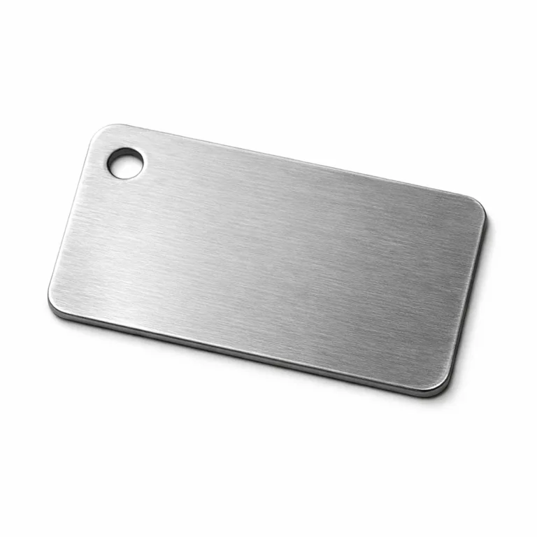 A high-detail studio image of an embossed garment tag made from brushed stainless steel with a matte finish. The tag has rounded corners and a single hole for sewing, showcasing sophisticated design and durability.