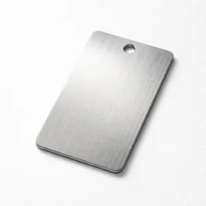 Brushed stainless steel garment tag designed for garments, featuring debossed front detail and rounded corners. The tag includes a single sewing hole for easy attachment and a modern blank emblem shape.