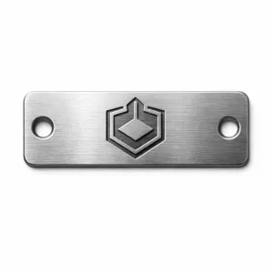 A realistic photo of a brushed stainless steel garment brand tag, featuring rounded corners, deep laser-engraved emblem, and two precisely punched rivet holes, shot on a white background. Designed for attaching to clothing as a durable and modern identity tag.