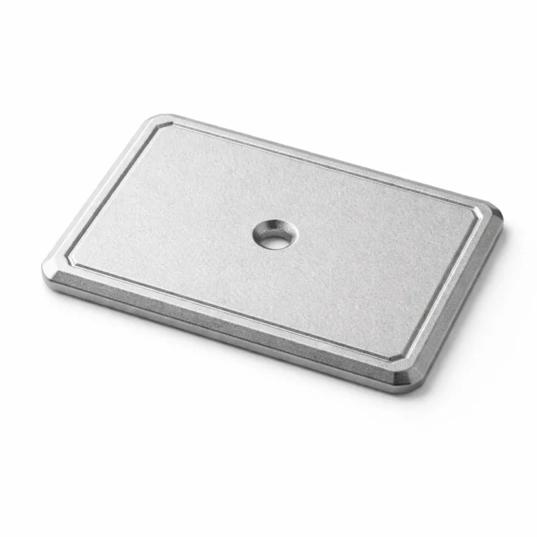 A matte anodized aluminum garment tag with a sandblasted finish, featuring beveled edges for a refined look, a single central sewing hole, and a lightly debossed border for added distinction.
