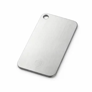 A realistic brushed stainless steel garment tag featuring rounded corners, a single hole for attachment, and a subtle blank emblem laser-engraved into the surface. Captured in a commercial studio setting with sharp detail, perfect for e-commerce.