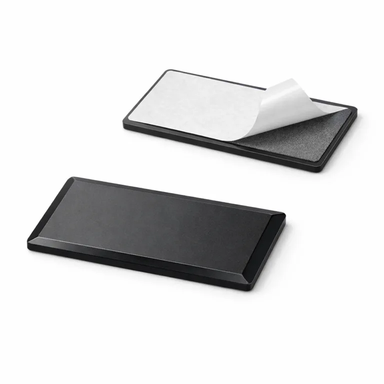 An anodized aluminum logo tag with a matte black surface, smooth beveled edges, and sturdy adhesive backing for easy mounting. Displays a debossed emblem shape with no readable text.