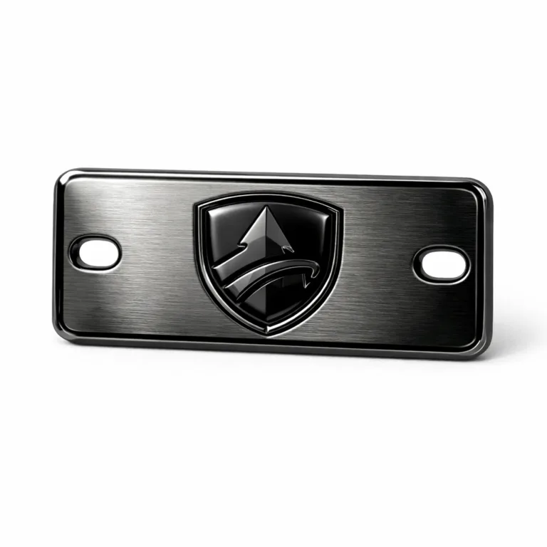 A studio shot of a logo tag made from brushed stainless steel with black nickel plating. The tag has rounded corners and a deep embossed emblem in the center for a premium, tactile effect.