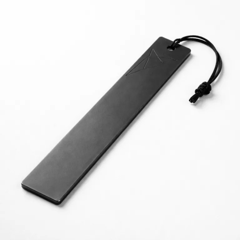 A long bar bookmark tag crafted from matte black anodized aluminum, showcasing precise chamfered edges and an etched accent pattern for added dimensionality.