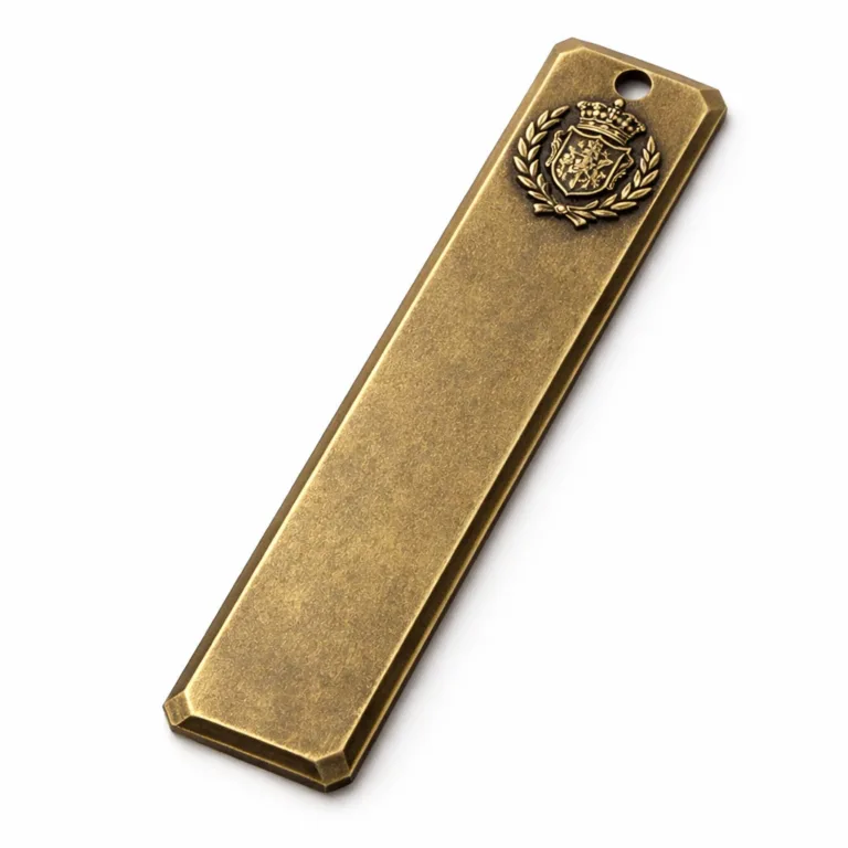 A long bar bookmark tag finished in antique brass, designed with beveled edging and a raised embossed emblem for a vintage, tactile appearance.