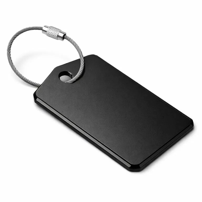 A luggage tag made from anodized aluminum, finished in matte black with beveled edges. Comes with a stainless steel split ring for easy fastening.