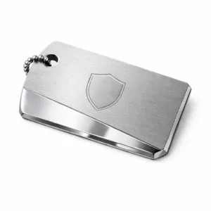 A two-tone luggage tag crafted from brushed stainless steel, featuring a distinctive beveled edge and a single hole for ball chain attachment. The tag displays a subtle blank emblem, created by laser engraving on the front surface for a refined look.