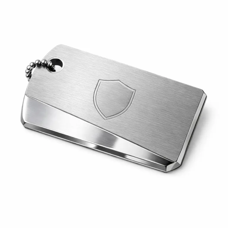 A two-tone luggage tag crafted from brushed stainless steel, featuring a distinctive beveled edge and a single hole for ball chain attachment. The tag displays a subtle blank emblem, created by laser engraving on the front surface for a refined look.