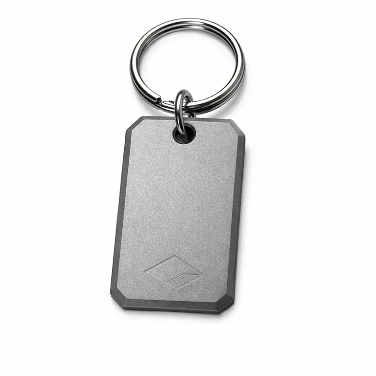 An anodized aluminum keychain tag in a matte sandblasted finish with a beveled edge design. Features a split ring attachment and a subtle etched blank emblem, ideal for lightweight and modern key organization.