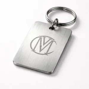 A single brushed stainless steel bag tag, featuring a laser-engraved monogram logo with rounded corners and a secure split ring attachment. Crisp studio lighting highlights the brushed texture and precise engraving.