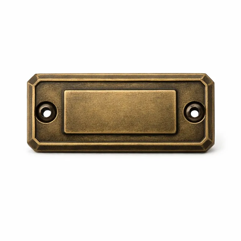 Premium Outerwear Metal Tag composed of thick zinc alloy with antique brass finish, chamfered edges lend a premium look, featuring two screw holes for mounting and a central embossed blank emblem for design versatility.