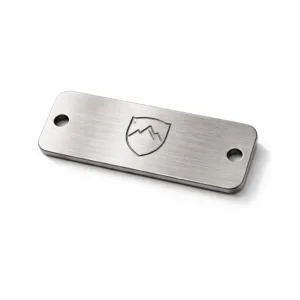 Premium Outerwear Metal Tag crafted from brushed stainless steel, features a rectangular profile with rounded corners, double sewing holes for garment attachment, and a laser engraved blank emblem for customizable branding.