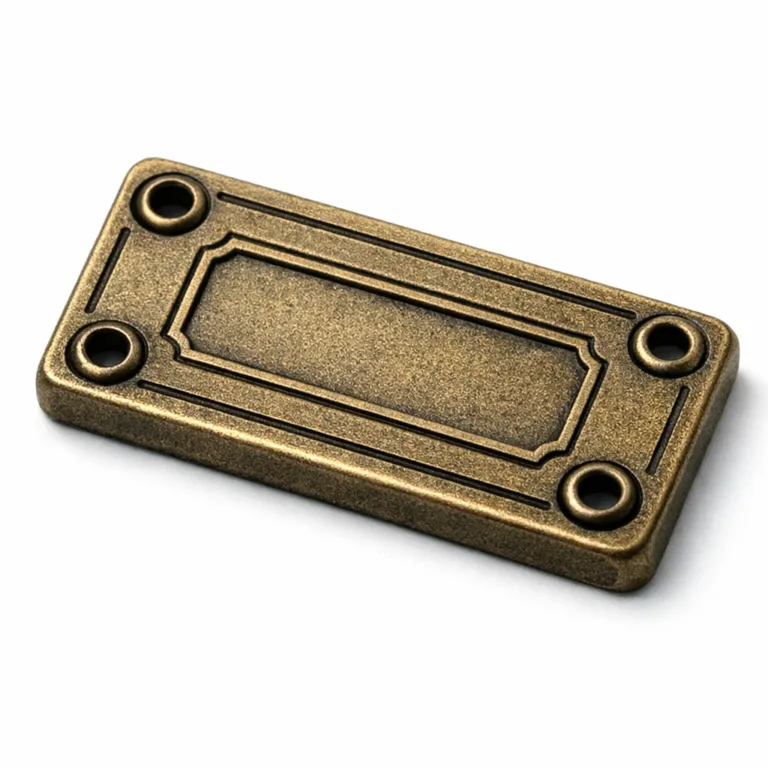 An antique brass-plated garment tag with a sandblasted matte finish, featuring a thicker profile, rivet holes for attachment, and detailed embossing alongside stamping. Suited for vintage-inspired garment serial number identification.