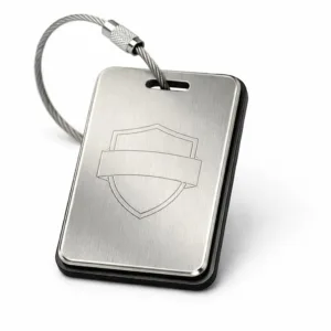 A two-layer bag tag featuring brushed stainless steel with rounded corners and beveled edge, highlighted by a subtle laser engraved blank emblem outline for customization. Studio-lit on a white background for sharp product focus.