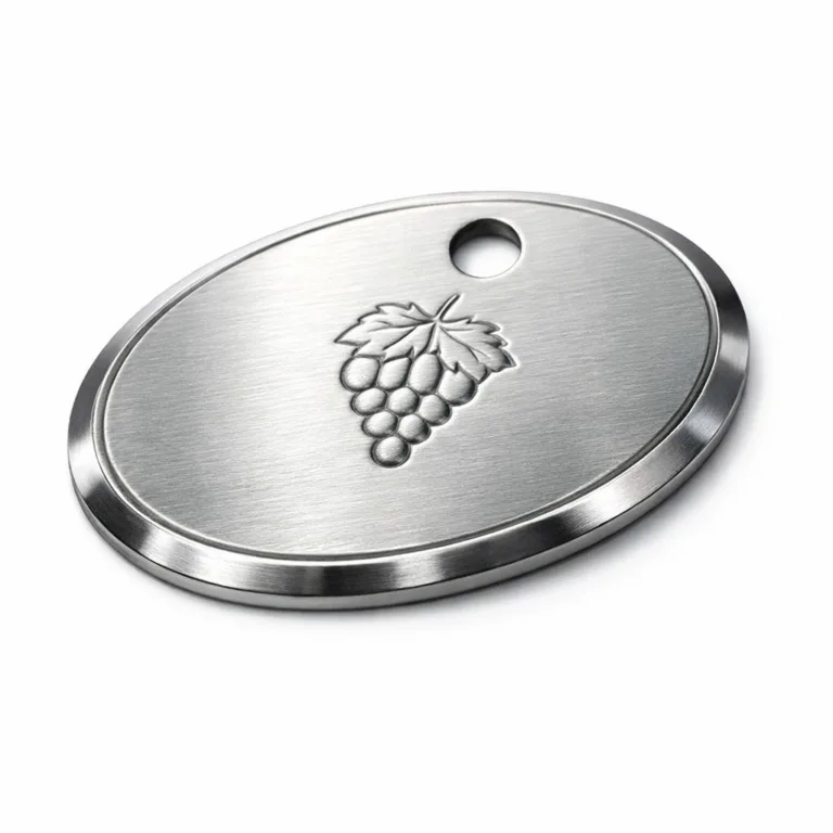 A high-detail, brushed stainless steel wine bottle tag featuring an oval shape, beveled edging, and a subtle embossed emblem. Designed with a single hole for easy attachment to a bottle neck.
