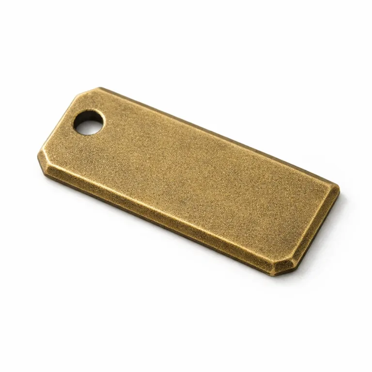 An antique brass-finished bookmark tag with a sandblasted matte texture, rectangular form, chamfered edge, and a single hole positioned at the corner for attachment.