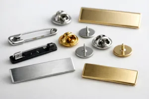 An accurate, well-lit display of safety pins and clutch pins positioned through metal tags, showing real manufacturing finish and attachment method.