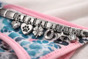 Cinematic photo showing tiny 8mm metal tags with engraved designs on a modern bracelet and bikini, highlighting surface finish and attachment detail.