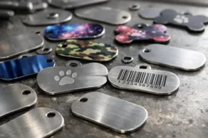 A photo-realistic scene showing several engraved dog tags and printed dog tags laid out on an industrial workbench, demonstrating the visual and structural differences in marking styles and durability.