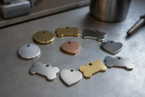 A cinematic close-up photo showing different small dog tags—circle, bone, heart shapes—in stainless steel, aluminum, and brass, arranged in an industrial studio with professional lighting.