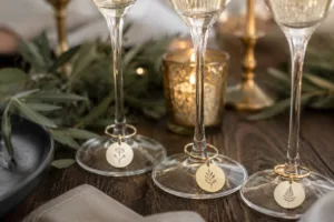 Champagne charms on glassware with custom branding, displayed in a sophisticated celebration table arrangement.