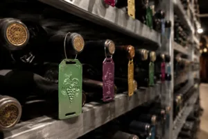 Photo-realistic depiction showing anodized metal color-coded tags attached to wine bottles in a cellar, emphasizing visual organization and durable materials.