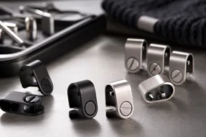 A realistic studio-style image showing small branding clips designed for caps and beanies in a production setting.