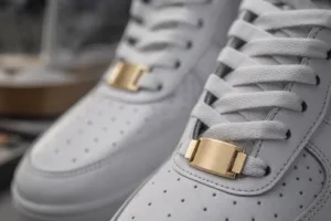 A detailed close-up showing custom metal dubrae tags enhancing the look of sneaker laces in a premium product setting.