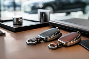 A premium visual showing leather and metal dealership key fobs as branded customer touchpoints.
